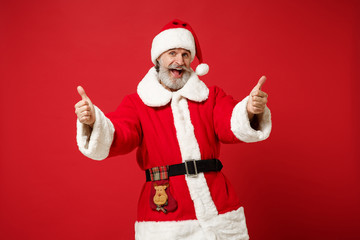 Fototapeta na wymiar Cheerful elderly gray-haired mustache bearded Santa man in Christmas hat posing isolated on red wall background. Happy New Year 2020 celebration holiday concept. Mock up copy space. Showing thumbs up.