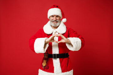 Fototapeta na wymiar Elderly gray-haired mustache bearded Santa man in Christmas hat posing isolated on red background. Happy New Year 2020 celebration holiday concept. Mock up copy space. Showing shape heart with hands.