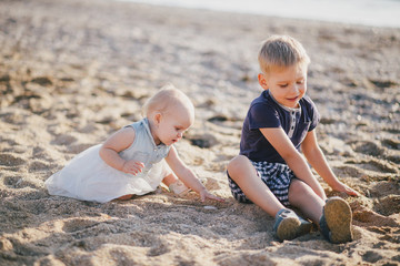 Little brother and sister posing near sea at beach