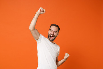 Cheerful happy young man in casual white t-shirt posing isolated on bright orange wall background...