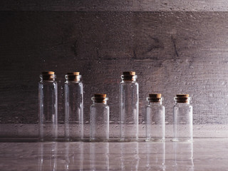 Small glass bottles with cork lid. empty bubbles in contoured light on wooden background, great...