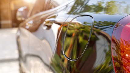 Close up shot of a car's fuel tank lid.with warm light. black car.