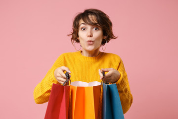 Amazed young brunette woman girl in yellow sweater posing isolated on pink wall background in...