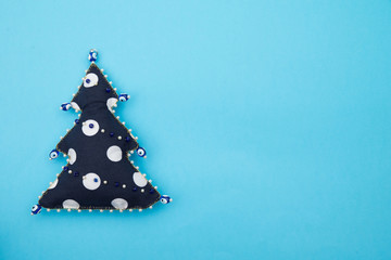 Handmade polka dot textile fabric naive retro style Christmas tree ornament decorated with beads on blue background with space for text