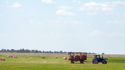 Tractor loading hay bales on truck agricultural works