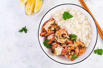 Grilled shrimps and boiled rice. King prawn tails in orange-garlic sauce with parsley. Top view, copy space