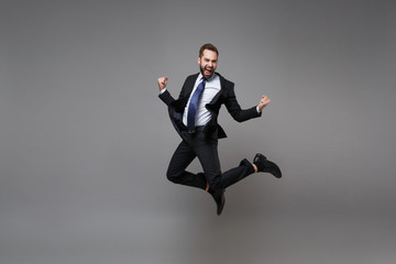 Joyful young business man in classic black suit shirt tie posing isolated on grey background....