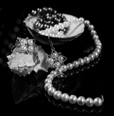 Composition of jewelry and bijouterie on a dark background with beautiful wine glasses and shells