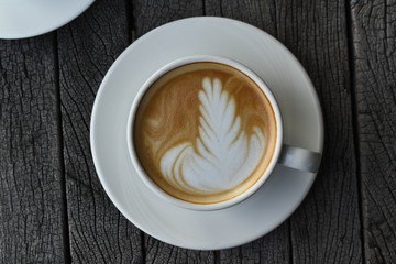 Close up a white coffee cup with heart shape on wood desk