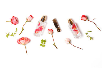 Essential aroma oil with roses on wooden background. Beauty workspace with roses, cosmetics. Top view. Flat lay home feminine desk.