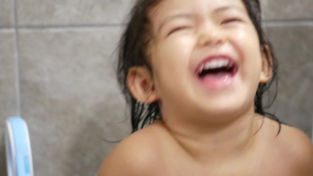 Close up of happy little Asian, Thai, baby girl, 2 years old, after taking a shower, smiling and laughing in a good mood at a camera