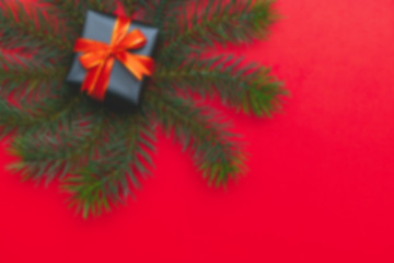 Blur background of top view of Christmas gift box red balls with spruce branches, pine cones, red berries and bell on red background.