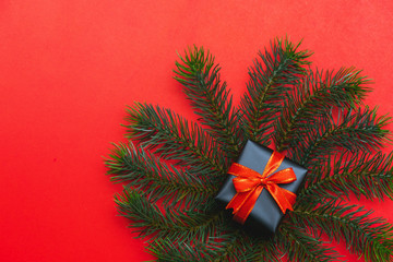 Top view of Christmas gift box red balls with spruce branches, pine cones, red berries and bell on red background.