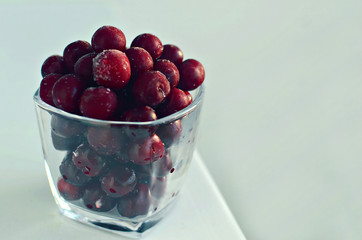frozen cherry in glass on white background, copy space