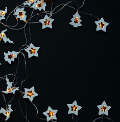 garland of stars, light bulbs for the new year holiday, on a black background, copy space