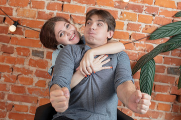 Funny couple fooling around on brick wall background