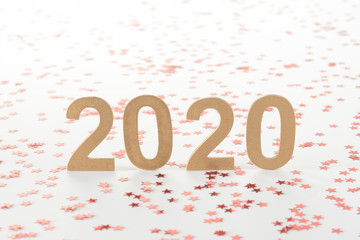 Año nuevo de 2020 en números dorados sobre fondo blanco y confeti rojo en forma de estrellas