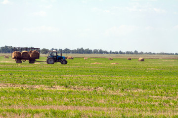 Tractor loading hay bales on truck agricultural works