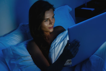 Young woman is using laptop computer at the night time © blackday