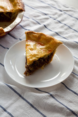 Tasty Homemade Canadian Tourtiere Meat Pie on a white plate , side view. Close-up.