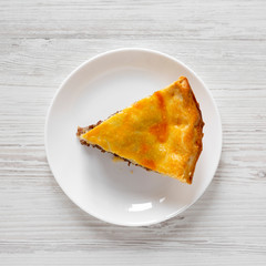 Slice of Homemade Canadian Tourtiere meat pie on a white plate over white wooden background, top view. Flat lay, overhead, from above. Closeup.
