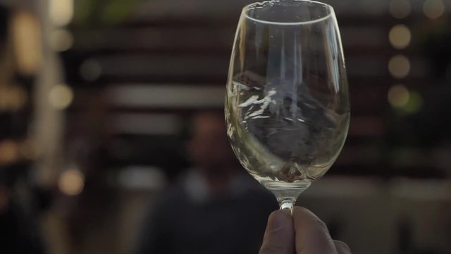 Wine tasting celebrations. Hand swirling white wine glass in quality taste, aroma testing.