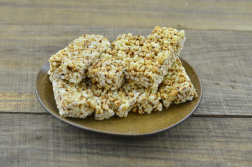 Cereal bars in brown plate on wooden background.
