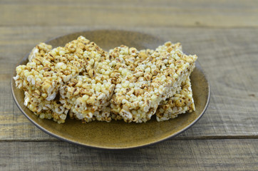 Cereal bars in brown plate on wooden background.