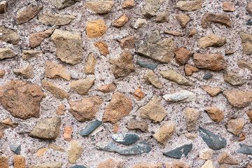 Old stone wall of stones of different sizes and colors as a natural background.