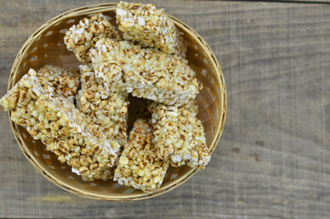 Cereal bars in bamboo basket on wooden background.