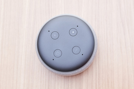 third generation amazon echo dot, white, top view four buttons, on a light wooden table