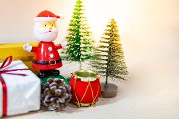 Christmas decoration concept. Santa Claus toy, gift box, pine cone and mini Christmas tree on the table. Decorative objects for Xmas and New Year holiday. Ornament for Festive season and celebration 