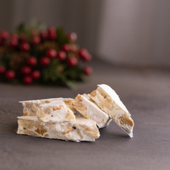Turron, typical Christmas sweet in Spain. Almond nougat on dark wooden background with Christmas decoration