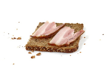 Slice of wholemeal dark bread with smoked bacon isolated on a white background, close-up 