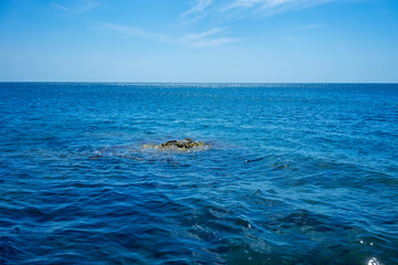 Seascape with a small rock on the background of water