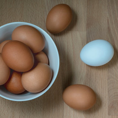 several fresh chicken eggs in a ceramic cup on a wooden background. Healthy eating concept