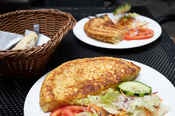 Tortilla Spanish omelette made with eggs and potatoes  on  served with traditional salad at spanish restaurant. Lifestyle image