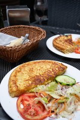 Tortilla Spanish omelette made with eggs and potatoes  on  served with traditional salad at spanish restaurant. Lifestyle image