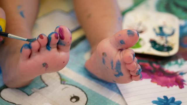 Selective focus and close up of a little baby's toes / feet being painted - painting helps developing child's hand-eye coordination