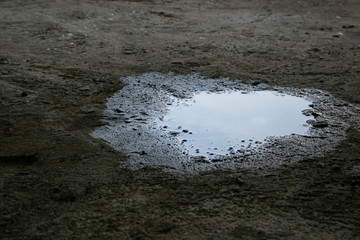 Close-up of spilled water leak on concrete floor of thebuilding. Wet floor because of pipelines or rain leakage from the roof in rainy day. Danger accident at home from a slippery floor hazard.