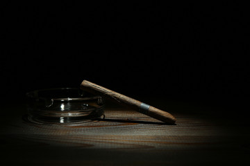 cigar and ashtray on dark background