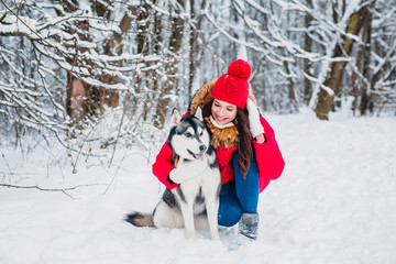 Fototapeta na wymiar Girl with her cute dog husky in the winter park