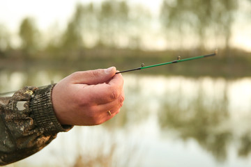 hands of a fisherman hold a fishing rod