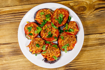 Baked eggplants with tomatoes and cheese on wooden table. Top view