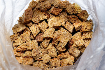 Close-up crackers or croutons of homemade rye bread in a plastic bag. Texture of slices of dry, crisp rye bread in a light bag. Blurred background.