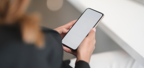 Cropped shot of young businesswoman using blank screen smartphone in modern office