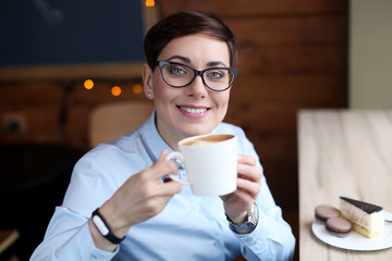 A woman with glasses and short hair a business Manager sits in a cafe near the window.