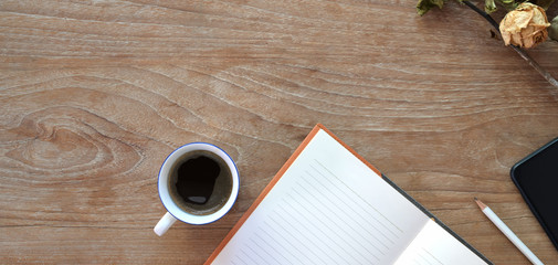 Top view of comfortable workplace with open notebook, coffee cup and copy space on wooden table