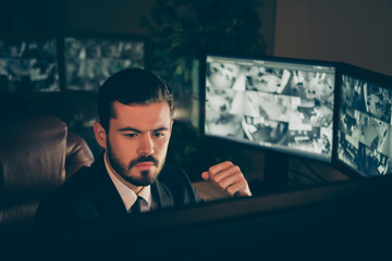 Close-up portrait of his he nice attractive qualified serious man safety expert supervising remote panel tv camera online protection management night shift late evening at work station place