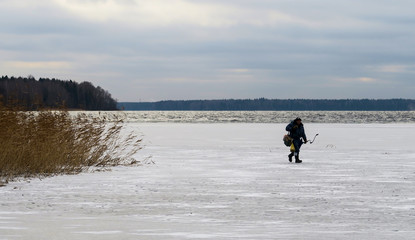 Winter fishing on the frozen river. Fishermen on the ice fishing in the hole.  Good biting fish in...